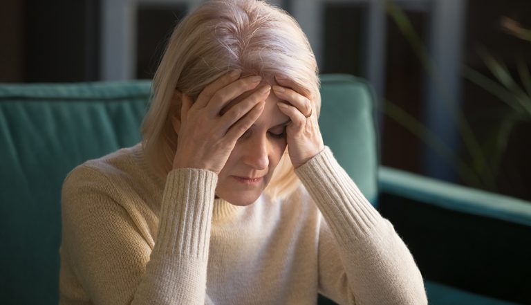 Upset stressed tired old mature woman coping with headache concept