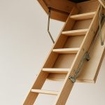 Wooden loft ladder extending from the ceiling, showing rungs and mechanism